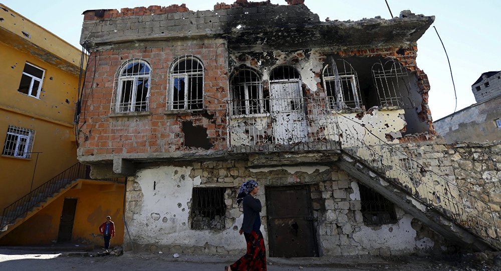 Uma mulher passa por um edifício que foi danificado durante confrontos entre forças de segurança turcas e militantes curdos, na cidade do sudeste de Silvan, na província de Diyarbakir, Turquia, 7 de dezembro de 2015. Foto tirada em 7 de dezembro de 2015. REUTERS / Murad Sezer