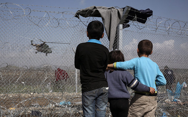 Children watch a helicopter fly over the refugee camp in Idomeni, as migrants and refugees wait to be allowed to cross the border with The Former Yugoslav Republic Of Macedonia (FYROM) in Idomeni, Greece