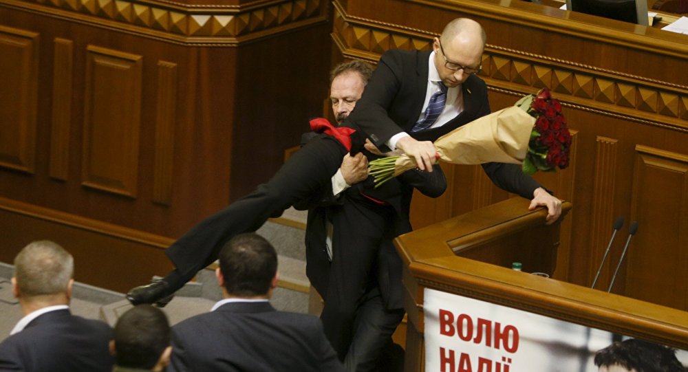 Oleg Barna, deputado da Rada, remove o primeiro-ministro Arseniy Yatsenyuk da tribuna, depois de lhe apresentar um buquê de rosas, durante a sessão do parlamento em Kiev, Ucrânia, 11 de dezembro de 2015