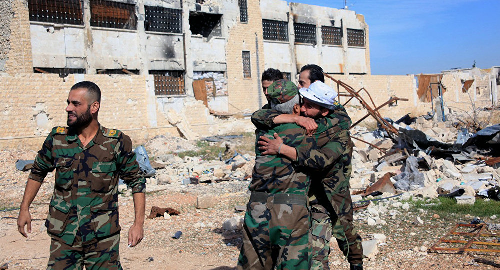 Soldados do governo sírio se abraçam em comemoração dentro da base aérea Kuweires, leste de Aleppo, Síria