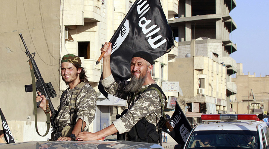 Militant Islamist fighters wave flags as they take part in a military parade along the streets of Syria's northern Raqqa province. © Stringer