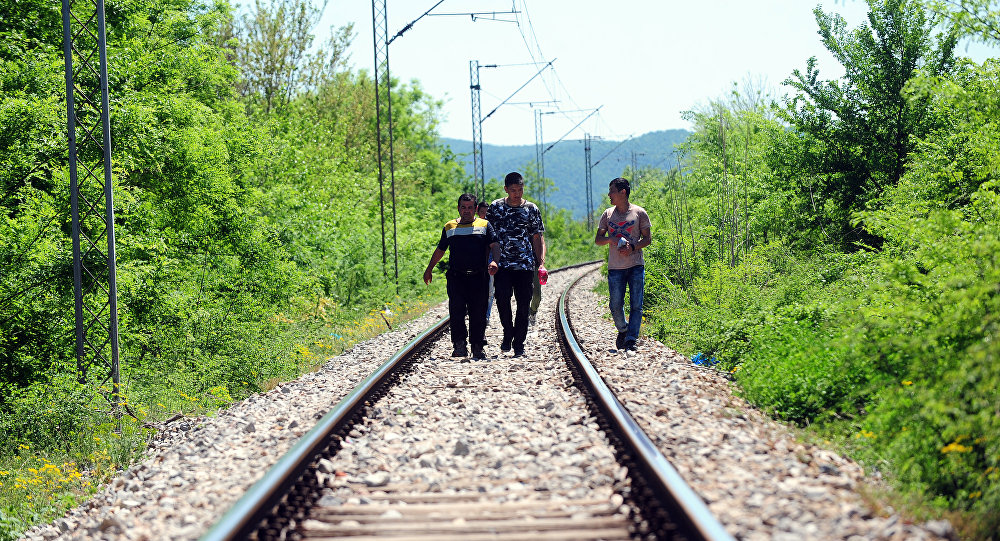 Refugiados seguem as trilhas de uma estrada de ferro perto da fronteira entre a Grécia e a Macedônia