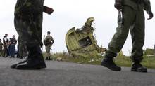 Armed pro-Russian separatists stand guard as monitors from the Organization for Security and Co-operation in Europe and members of a Malaysian air crash investigations team inspect the crash site of Malaysia Airlines Flight 17 near the village of Grabovo, Donetsk region, on July 22, 2014. (MAXIM ZMEYEV/REUTERS)